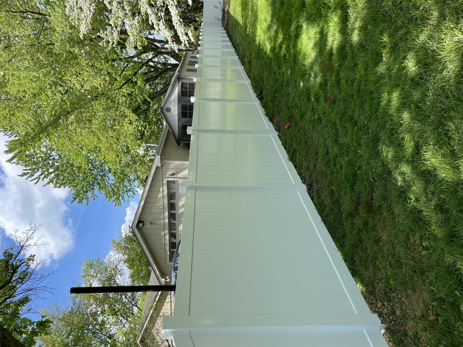 Completed white vinyl privacy fence surrounding a residential backyard